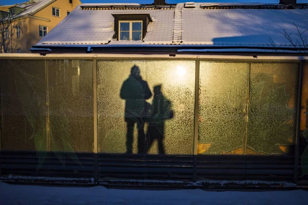 Stockholm, Sweden A man and a woman in shadow stand on the  Karrtorp subway or tunnelbana platform in the morning winter sun.