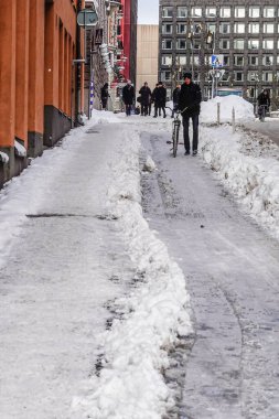 Stockholm, İsveç 'te bir yaya kaldırımı ve Malmtorgsgatan' da yan yana sürülen bir bisiklet yolu ve bisikletini gezdiren bir adam..