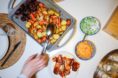 Izgara patates, havuç, pancar, humus ve kızarmış halloumi peyniri olan bir yemek masası..