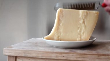 Bir kalıp parmesan peyniri tabakta rendelenir.