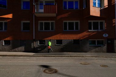 Trollhattan, İsveç Elle üfleyen bir adam sokakları kumdan ve çakıldan temizliyor.