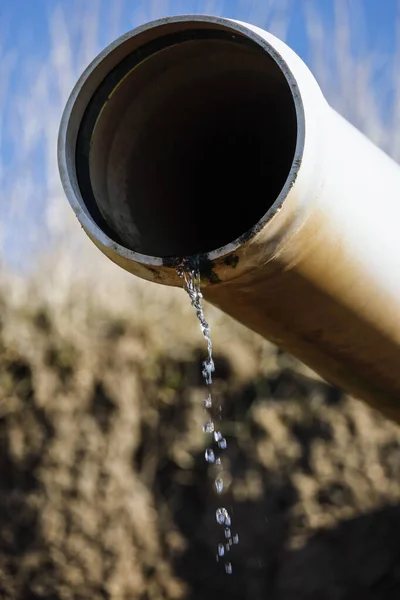 A drainage pipe in a field drips water