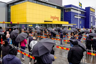 Stockholm, İsveç 'te insanlar, mağazadan sağlanan şemsiyeli salgın nedeniyle yağmurda bir IKEA mağazasının önünde bekliyorlar..