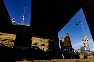 Stockholm, İsveç İnsanlar gün batımında Liljeholmen köprüsünün altında yürüyor.