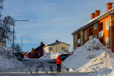 Kiruna, İsveç Bir kadın köpeğini güneş batarken gezdiriyor meskun bir sokakta.