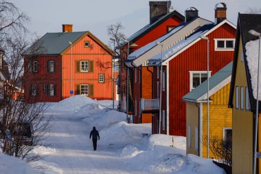 Kiruna, İsveç, İlkbaharda bir adam bir yerleşim bölgesinde kar yığınlarıyla yürüyor..