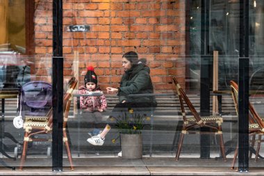 Stockholm, İsveç. Genç bir kadın kızıyla açık bir kafede kahvaltı yapıyor..