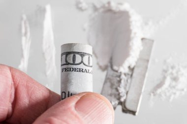 Ustura ve Amerikan parasıyla kokain çekmek için sarılmış bir yığın beyaz uyuşturucu..