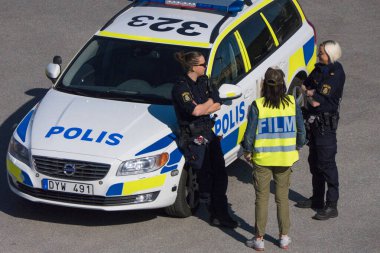 Stockholm, İsveç. Bir polis arabası ve bir film ekibiyle konuşuyor..