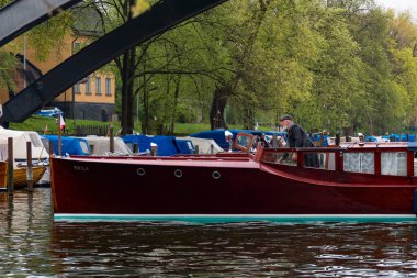 Stockholm, İsveç 'te bir adam Sodermalm' daki Palsundet Kanalı 'nda klasik bir ahşap tekne manevrası yapıyor..