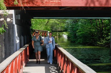 Stockholm, İsveç Halk, Ulvsunda banliyösündeki bir kanalın yanındaki köprünün altında yaya yolunda yürüyor..