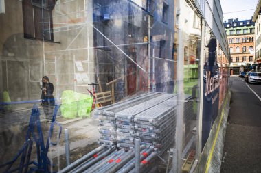 Stockholm, İsveç 'te telefondaki bir kadın bir inşaat sahasının plastc kapağına yansıyor..