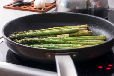 Mevsimlik kuşkonmaz fırının tepesinde yağlı bir tavada kızarıyor..