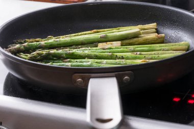 Mevsimlik kuşkonmaz fırının tepesinde yağlı bir tavada kızarıyor..