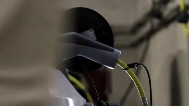 Bir adam elektrikli bir araca fiş takıyor.