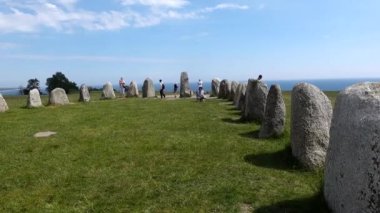İsveç, Ales Stenar Güney İsveç 'te gemi şeklinde 1000 yıllık kaya oluşumunun ortasında yürüyen bir turist..
