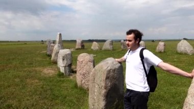 İsveç, Ales Stenar Güney İsveç 'te gemi şeklinde 1000 yıllık kaya oluşumunun ortasında yürüyen bir turist..