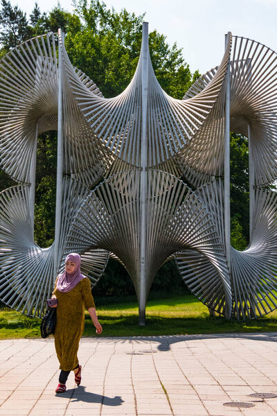 Stockholm, Sweden A Muslim woman walks by a 1975 sculpture on the main square in the Fisksatra suburb called Arkitekta Skulpturum by artist Bertil Herlov Svensson.