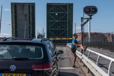 Stockholm, İsveç 'te bir koşucu Liljeholmsbron ya da Liljeholmens köprüsündeki trafiği aşarken köprü alttaki tekneler için yükselir..