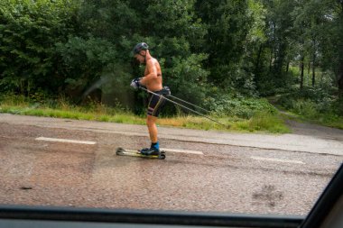 Stockholm, İsveç 'te bir adam yol kenarında paten kayıyor. Araba camı çerçeveli..