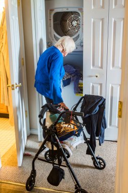 Yürüteci olan son sınıf bir kadın evde çamaşır yıkıyor..