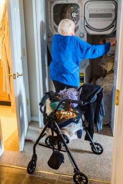 Yürüteci olan son sınıf bir kadın evde çamaşır yıkıyor..