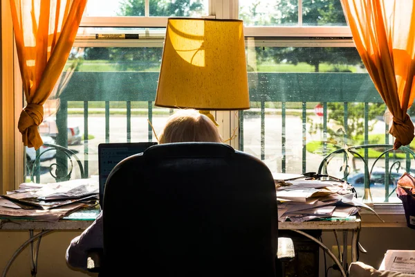 Uma Mulher Idosa Senta Uma Mesa Bagunçada Frente Janela — Fotografia de Stock