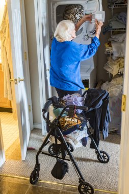 Yürüteci olan son sınıf bir kadın evde çamaşır yıkıyor..