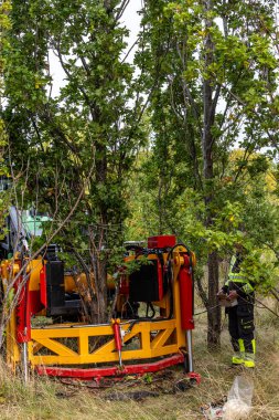 Stockholm, İsveç 7 Ekim 2025 ormandaki büyük eklemli bir buldozer ağaç ve kökleri yerden çıkarmak için bir kepçe ile donatılmıştır..