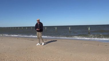 Chesapeake Sahili, Maryland. Güneşli bir sonbahar gününde Chesapeake Körfezi kıyısında yürüyen bir adam..