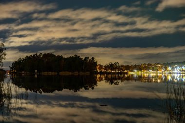 Stockholm, İsveç Solna ve Danderyd banliyöleri arasında küçük bir koy olan Edsviken 'in suları üzerinde bir gece manzarası ve bulutlu bir yer..