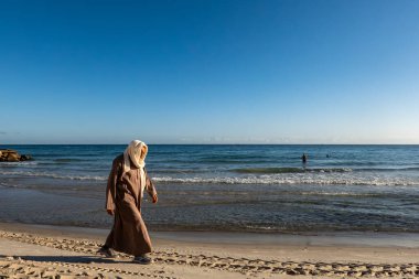 Susa, Tunus 3 Kasım 2025 Berberi cüppeli bir adam sahilde yürüyor..