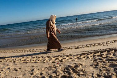 Susa, Tunus 3 Kasım 2025 Berberi cüppeli bir adam sahilde yürüyor..