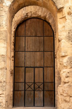 El Jem, Tunus 6 Kasım 2025 El Jem Roma amfitiyatrosunun kalıntıları arasında büyük ahşap bir kapı..