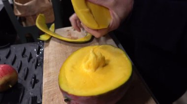 Stockholm, İsveç Bir aşçı evcil bir mutfakta büyük olgun bir mango meyvesi soyar. 