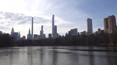 New York, New York ABD Central Park ve The Lake 'teki şehrin gökdelen manzarası. 