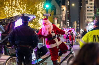 New York, New York, ABD Aralık 2025 Noel Baba gibi giyinmiş bir adam turistler için 5. Cadde 'de bisiklet rickshaw' u kullanıyor..