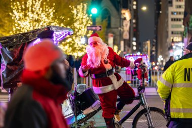 New York, New York, ABD Aralık 2025 Noel Baba gibi giyinmiş bir adam turistler için 5. Cadde 'de bisiklet rickshaw' u kullanıyor..
