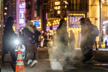 New York, New York, ABD 9 Aralık 2025 gece şehir merkezindeki 6. Cadde 'de buharlı ve farlı yayalar..