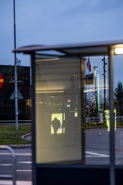 Stockholm, İsveç 11 Aralık 2025 Arlanda Havaalanı 'ndaki otobüs durağı kaldırımdaki bir yolcunun gölgesini yansıtıyor..