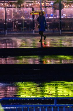 Stockholm, İsveç 13 Aralık 2025. Liljeholmskajen bölgesinde yağmurda yürüyen şemsiyeli bir kadın yaya.