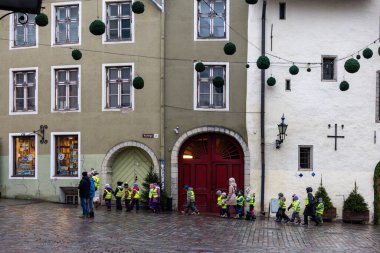 Tallinn, Estonya 15 Aralık 2025 Eski Twon 'da sarı yansıtıcı ceketli bir grup anaokulu öğrencisi yürüyüş yapıyor..
