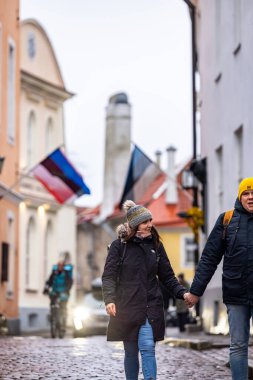 Tallinn, Estonya 15 Aralık 2025 Eski Şehir 'de yürüyen yaya bir çift ve Estonya bayrakları.