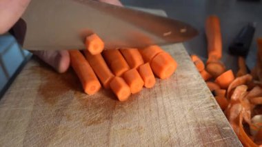 Stockholm, İsveç. Ahşap bir tahtanın üzerinde, mutfakta havuç doğrayıp doğrayan bir aşçı..