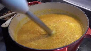 Stockholm, İsveç 'te bir aşçı el blenderi kullanarak havuç çorbasını kabın içinde püre yapar..