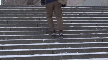 Stockholm, İsveç 'te botları olan bir adam kışın karlı basamaklara tırmanır..