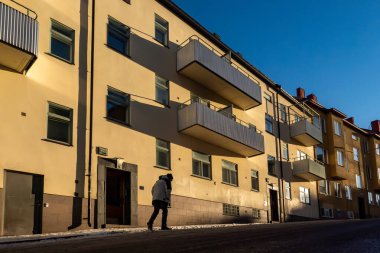 Stockholm, İsveç 28 Ocak 2026. Güneşli bir kış gününde Midsommarkransen bölgesinde bir tepeye çıkan bir adam..