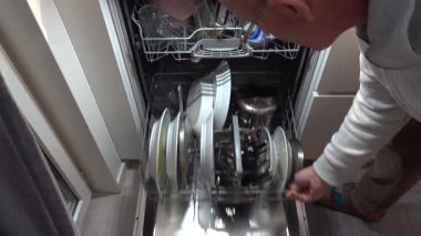 Stockholm, İsveç Bir adam bulaşık makinesini dolduruyor.