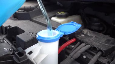 Stockholm, İsveç Mavi ve temiz cam sileceği sıvısı kışın elektrikli bir arabanın kaputunun altına dökülür..