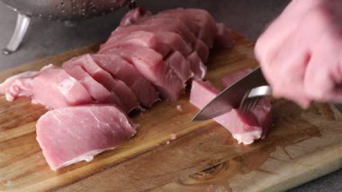 Stockholm, İsveç 'te bir adam güveç hazırlamak için tahta kesme tahtasına domuz filetosu dilimliyor..